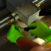 Image of two bright neon green nitrile disposable gloves being used to complete pipework